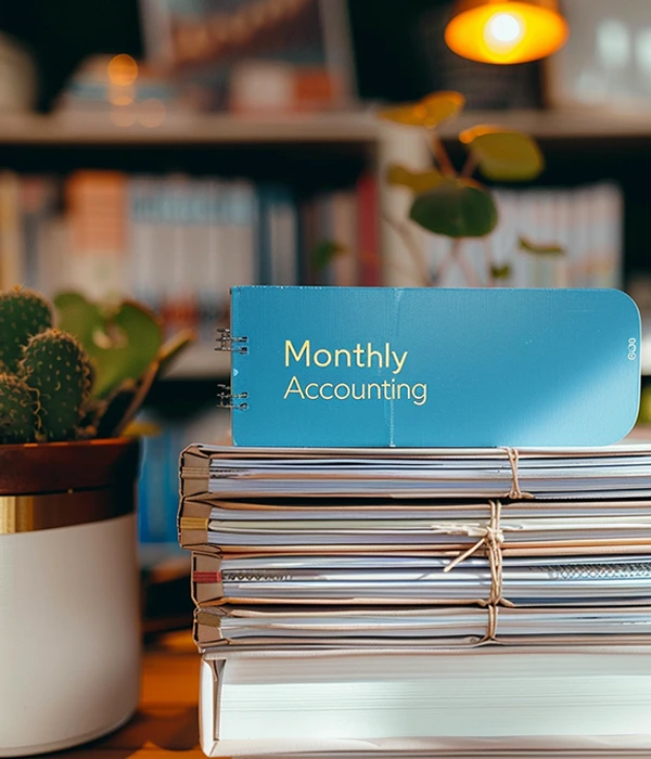 stack of books and the top one says monthly accounting